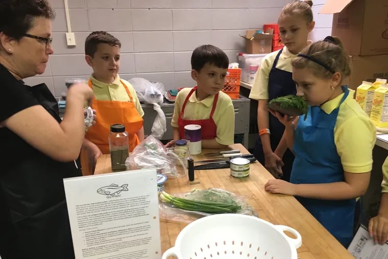 Taylor Gotts (far right) inhales the aroma of fresh dill as (from left) principal Jane Lockhart and students Joey Moore, Christopher Gallagher and Saige Adair look on.