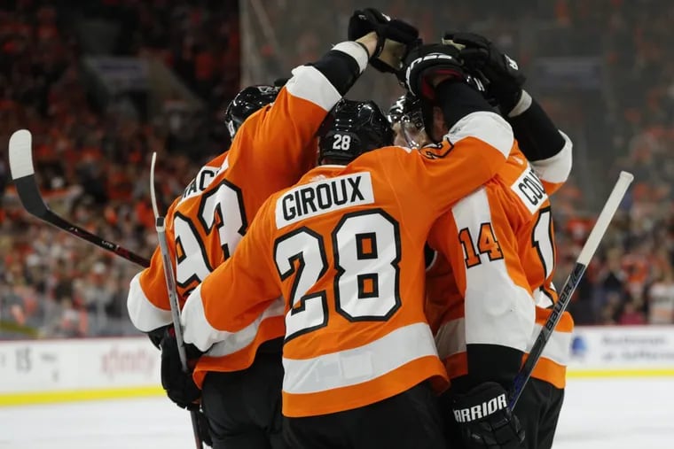 Flyers’ players Jake Voracek and Sean Couturier gather to celebrate the goal by Claude Giroux, center.