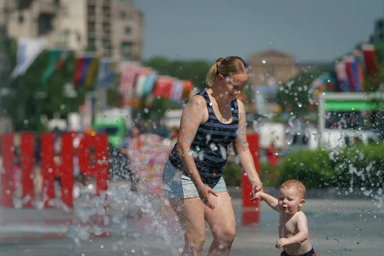 Lisa Russell, and her 1-year-old son Ian Banks Jr., cool off in the water feature at Love Park on a hot day last week.