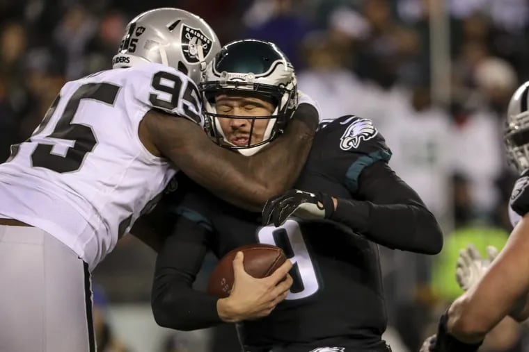 Quarterback Nick Foles is sacked by Oakland Raiders defensive lineman Jihad Ward in the third quarter of the Eagles’ 19-10 win Monday night.