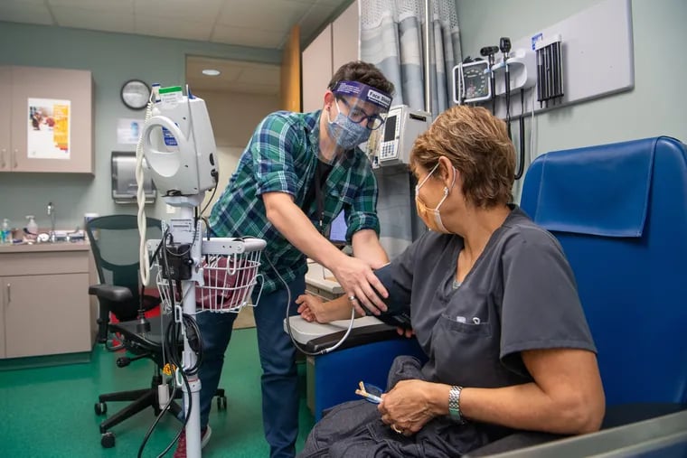 Juan Diego Ramirez, a clinical research coordinator at Penn Medicine, speaks to Enelida Gomez, a nurse in Philadelphia, before she receives the second dose of Moderna’s investigational mRNA COVID-19 vaccine as part of a clinical trial at Penn Medicine.