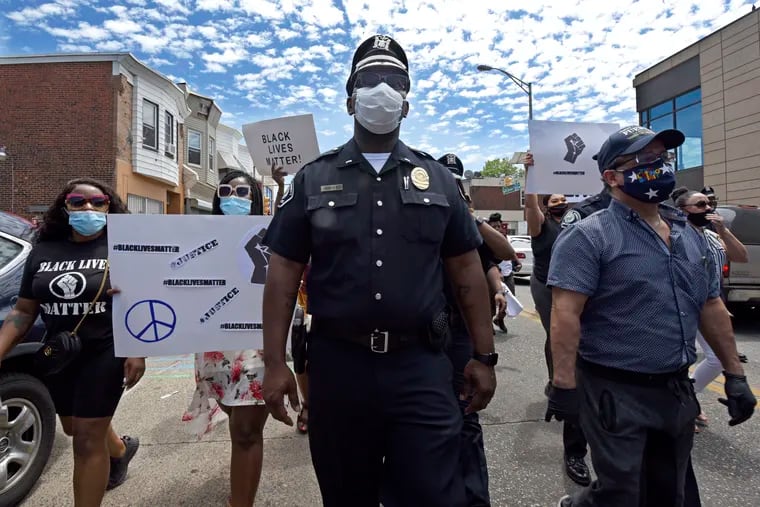 In this Saturday, May 30, 2020, photo, Lt. Zack James of the Camden County Metro Police Department marches along with demonstrators in Camden, N.J., to protest the death of George Floyd in Minneapolis.