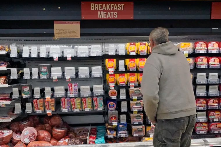 A shopper at a grocery in Pittsburgh looks at a partially empty display of breakfast meats.