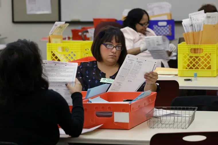 In this 2014 photo, Lydia Harris, a temporary worker at the Sacramento Registrar of Voters, looks over a mail-in ballot before it is sent to be counted in Sacramento, Calif.