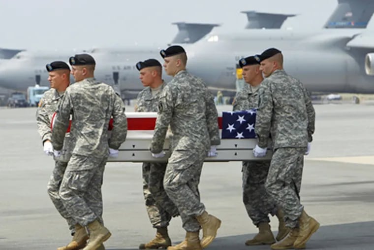 An Army team moves a transfer case with the remains of Staff Sgt. Kenneth VanGiesen at Dover (Del.) Air Force Base. (Ann Heisenfelt / Associated Press)
