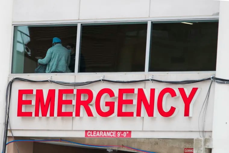 A physician is viewed through the window above the emergency room sign on April 17, 2020.