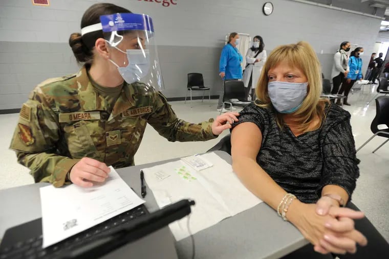Lisa Meincke of Arlington Heights prepares herself to receive her first COVID-19 vaccination administered by National Guard personal Erika O'Meara of Scott Air Force base at Triton College, Wednesday, Feb. 3, 2021, in River Grove, Ill. This was opening day for the mass vaccinations sponsored by the Cook County Department of Public Health.