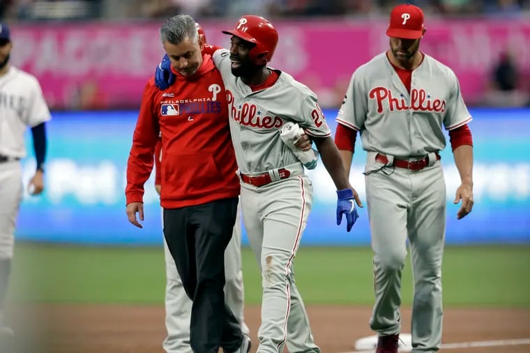 Outfielder Andrew McCutchen is helped off the field after injuring his knee in the first inning of the Phillies' 8-2 loss to the Padres on Monday.