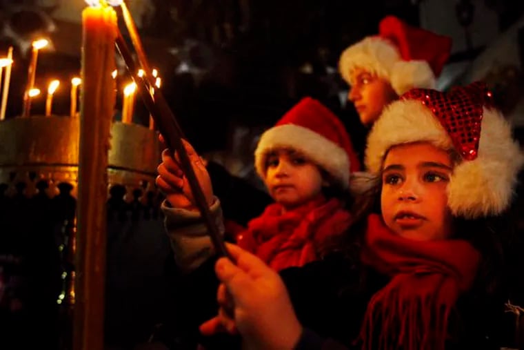 Palestinian Christian children light candles in the Church ofthe Nativity during Christmas celebrations in Bethlehem.