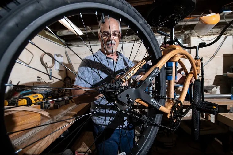 Joe Lavallee in his basement work studio with a solid oak beach cruiser he made by hand.