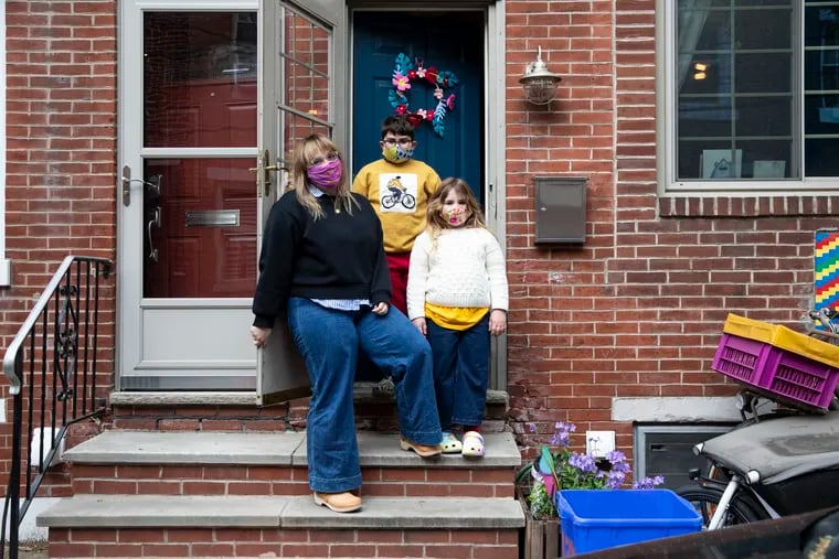 Dena Driscoll and her kids Milo, 9, and Juniper, 6, stand outside their home in the Passyunk Square neighborhood in Philadelphia. Getting the kids to wear masks has been a daily negotiation -- especially when so many other people are going out uncovered.