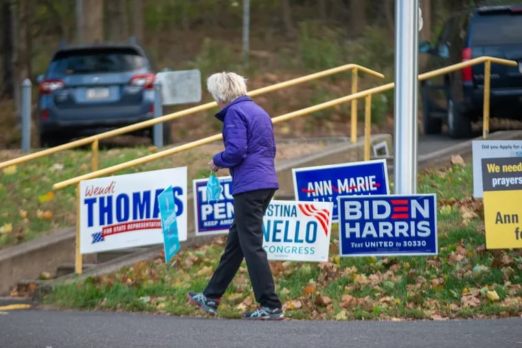 A woman walks past campaign signs on Election Day 2020 in New Hope.