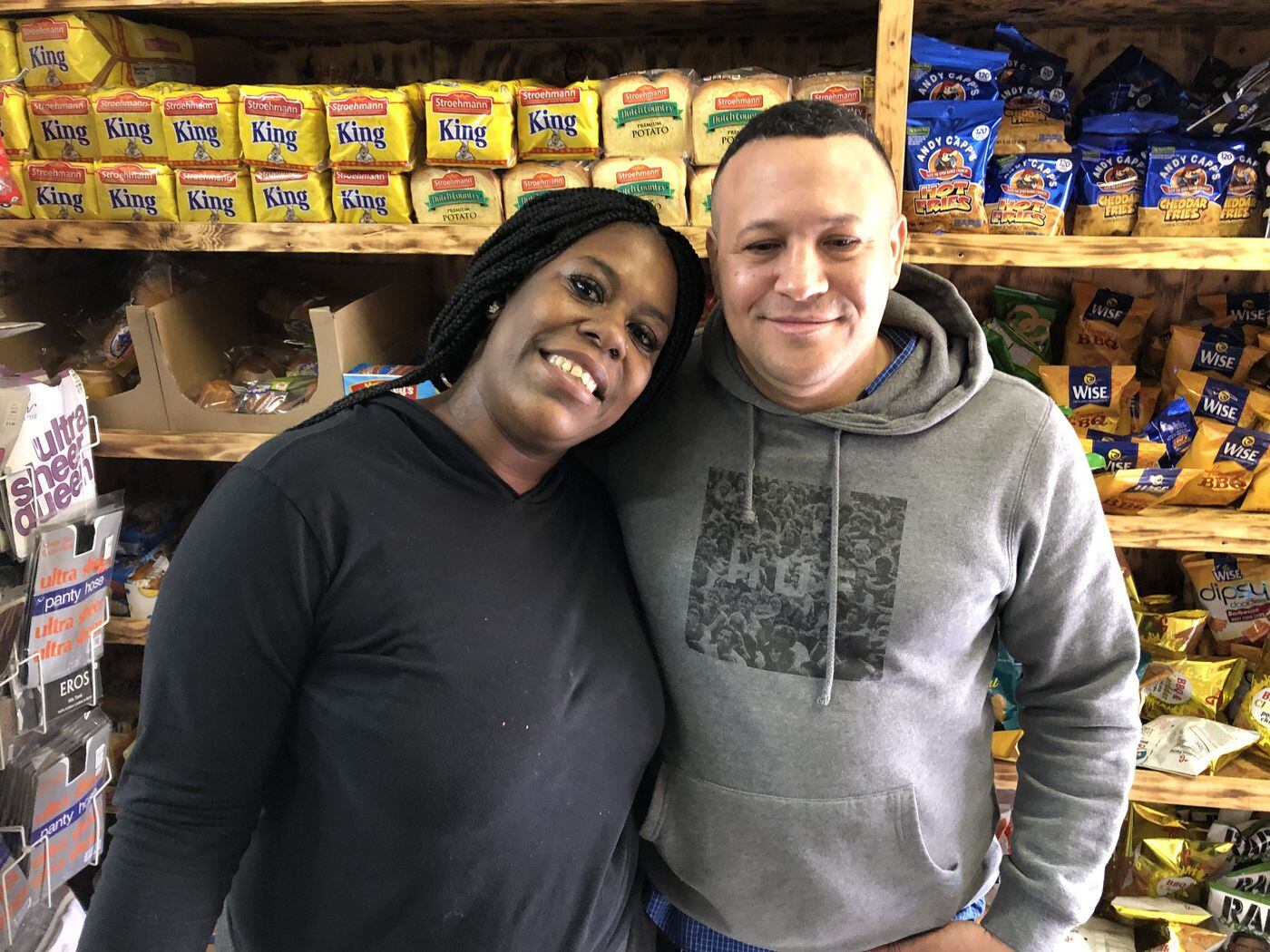 West Philly grocer Elvis Nuñez inside his store with customer Qiana Grant on March 18, 2019, four days after Nuñez was in a shootout with a would-be robber. Grant and other regulars at the store call Nuñez "Papi."