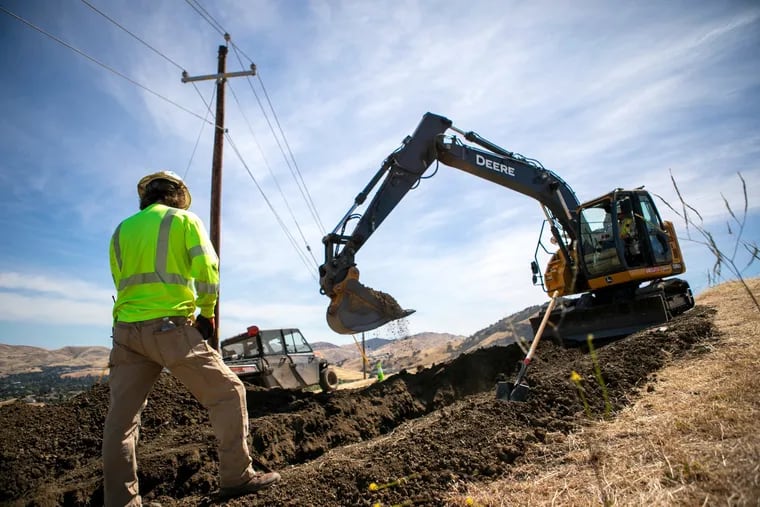 Tyler Owens, left, directs track hoe operator Alan King, both with the Underground Electric Construction Company, as they work to dig two lines of 6-inch conduit to the correct depth at the Lime Ridge Open Space in Walnut Creek, California, on Thursday, May 19, 2022. The conduit will carry Pacific Gas and Electric power lines underground and replace the existing above-ground lines to reduce the risk of wildfire ignitions. (Anda Chu/Bay Area News Group/TNS)