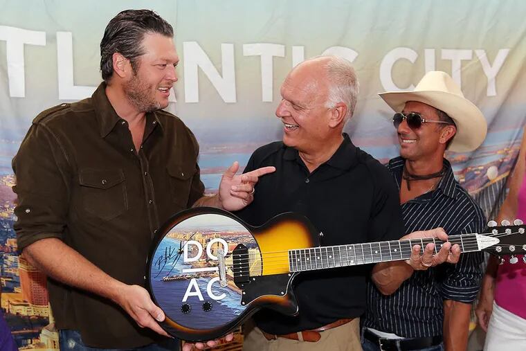 Blake Shelton, left, presents a guitar he signed to Atlantic City Mayor Don Guardian before his concert on the beach in Atlantic City, N.J., Thursday, July 31, 2014. (AP Photo/The Press of Atlantic City, Dale Gerhard) MANDATORY CREDIT