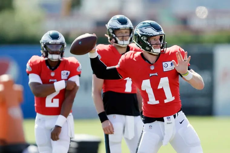 Eagles quarterback Carson Wentz throws the football as backup quarterbacks Nate Sudfeld, center, and Jalen Hurts watch on the first day of team training camp.