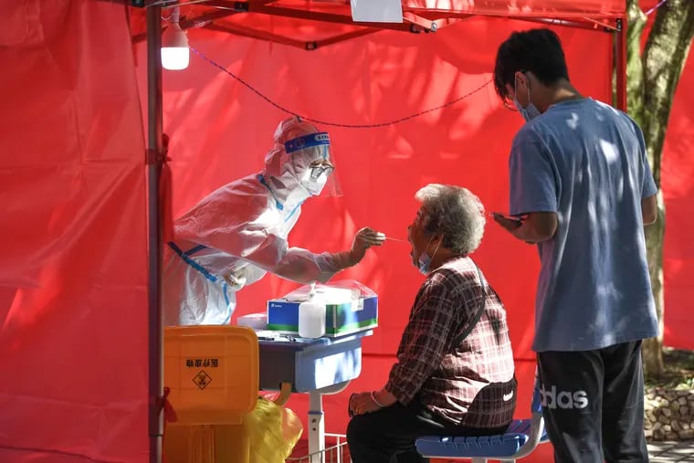 In this photo released by Xinhua News Agency, a medical worker takes a swab sample from a resident for nucleic acid test at a community testing site for COVID-19 in Yunyan District of Guiyang, southwest China's Guizhou Province.