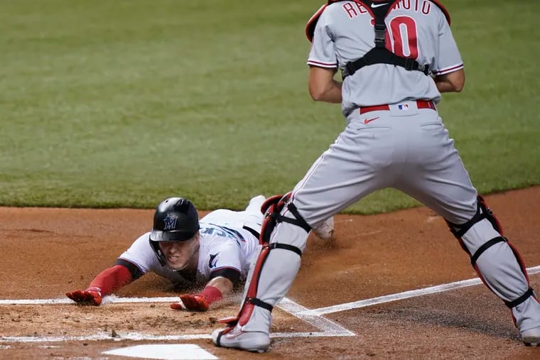 Miami Marlins' Corey Dickerson slides in safely at home to score on a double by Starling Marte as Philadelphia Phillies catcher J.T. Realmuto, right, waits for the throw during the first inning of a baseball game, Thursday, Sept. 10, 2020, in Miami. (AP Photo/Wilfredo Lee)