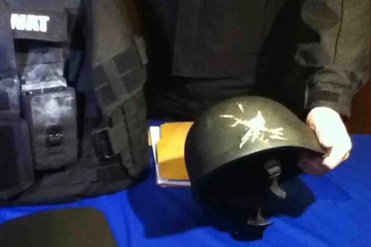 Officers display the helmet worn by Sgt. Christopher Binns, damaged when he was shot at during a standoff. His fellow officer, Francis Whalen, was protected by a Kevlar vest in the incident.