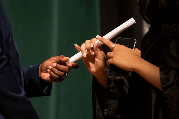 A principal hands a diploma to a student at the Philadelphia School District summer graduation in 2023.