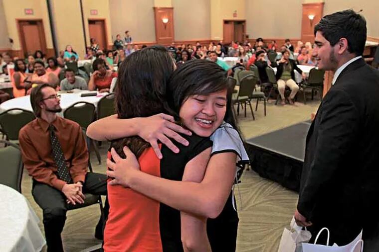 Yen Tran, from Pennsauken High School, right, gives AIM program assistant Nina Mercado, left, a big hug as she comes forward to recieve her graduation certificate from the 3 week program on the Rutgers campus Friday afternoon.  Rutgers–Camden Aim High Academy prepares and motivates rising 12th-grade students to attend and succeed in college by providing an early introduction to a Rutgers learning and living environment.  Forty S. Jersey high school students will be graduating from a 3-week college preparation program in which they were living on the Camden-Rutgers campus, learning about civic engagement and getting pumped for college. Today is their graduation from the program, they will receive diplomas.   07/25/2014 ( MICHAEL BRYANT  / Staff Photographer )