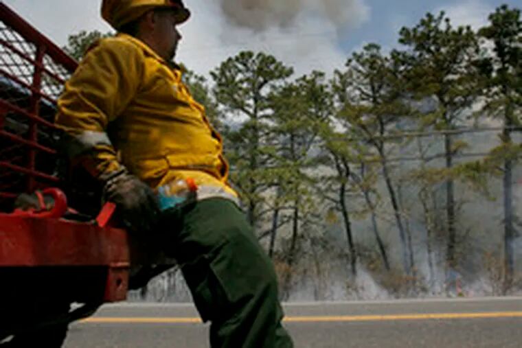 Mark Jenigen of the New Jersey Forest Fighter Services takes a break as smoke billows along Route 539 near Warren Grove, N.J. A military flare was believed to be the cause of the fire.