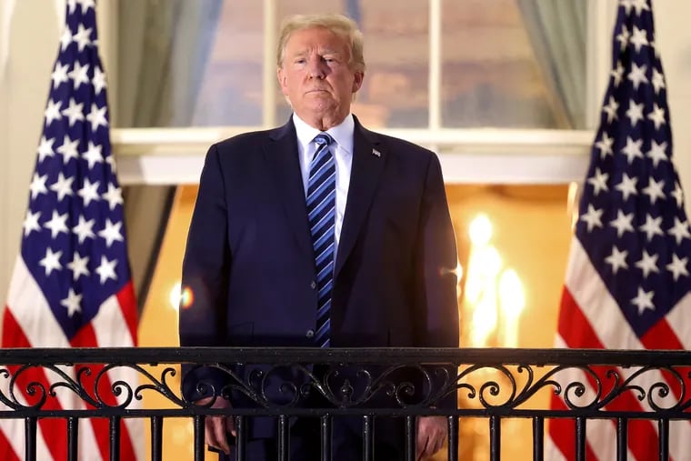 President Donald Trump stands on the Truman Balcony after returning to the White House from Walter Reed National Military Medical Center on Monday.