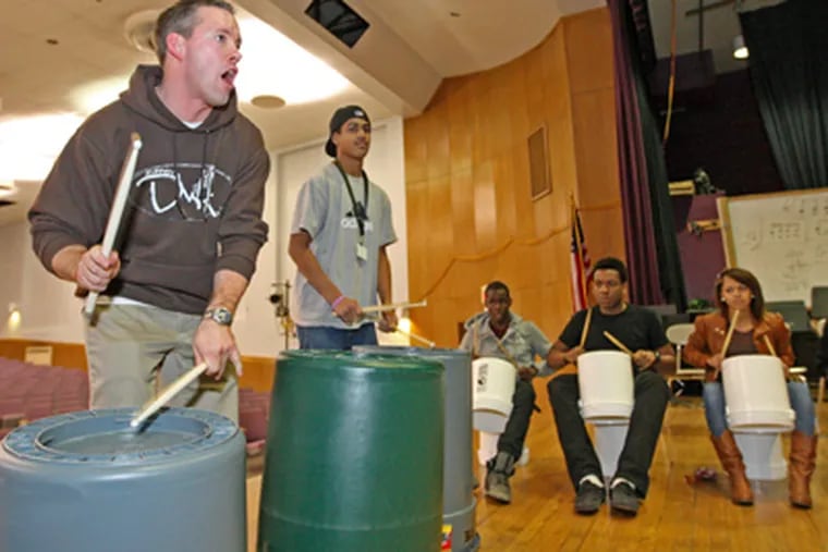 Drummers With Attitude founder Kevin Travers (left), a Bristol Township teacher, pounds a garbage can while leading a rehearsal at the Benjamin Franklin Freshman Academy. (Michael Bryant / Staff Photographer)