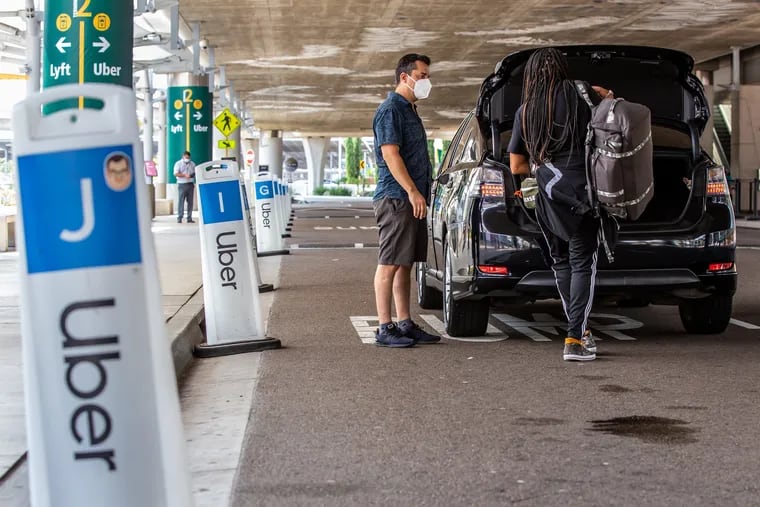 People wait for rideshare vehicles at the San Diego Airport. Some users will soon have to prove they're wearing a face mask, thanks to its latest safety mitigation measure.