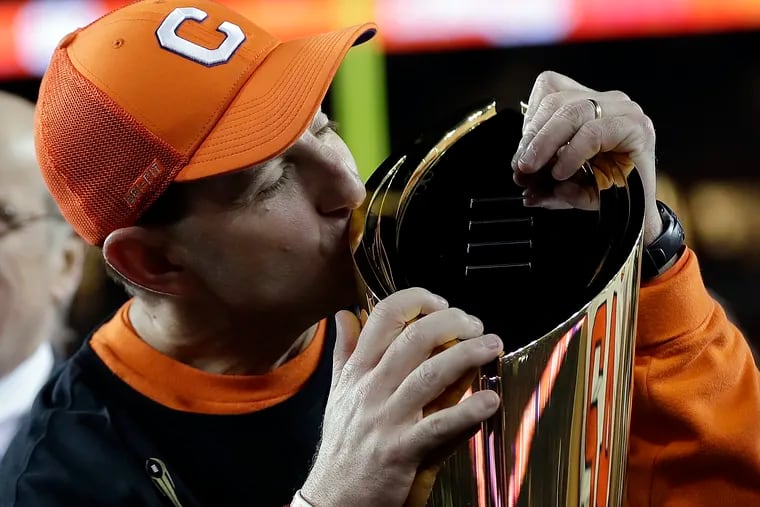 Clemson head coach Dabo Swinney kisses the championship trophy Monday night.