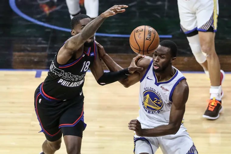 The Sixers'  Shake Milton and the Warriors' Andrew Wiggins fight for a loose ball in Monday's game.
