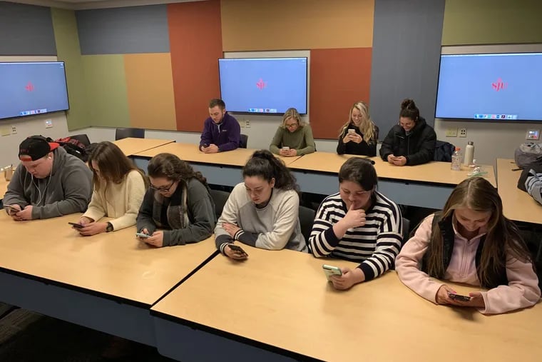 These undergrads at St. Joseph's University, pictured staring at their cells, gave up their smartphones for a day in January 2019, as an assignment for their professor, Inquirer columnist Maria Panaritis. What they discovered wasn't pretty.