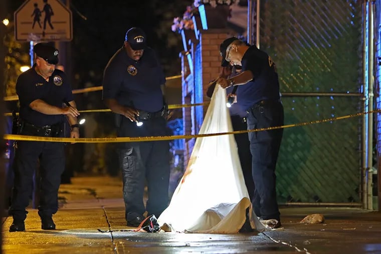 Investigators look under a sheet covering the victim’s body in Olney after the shooting. JOSEPH KACZMAREK / FOR THE DAILY NEWS