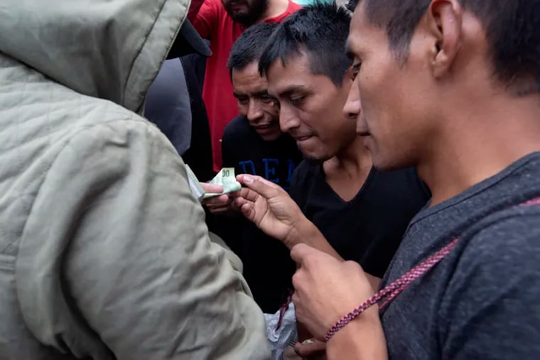 Guatemalan men who were deported from the United States, change money after arriving at the Air Force Base in Guatemala City, Tuesday, July 16, 2019. Nearly 200 Guatemalan migrants have been deported on Tuesday, the day the Trump administration planned to launch a drastic policy change designed to end asylum protections for most migrants who travel through another country to reach the United States.