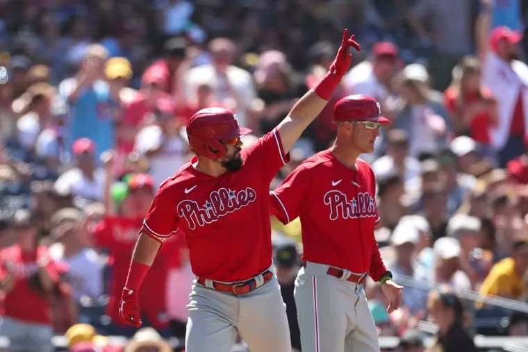 Philadelphia Phillies' Kyle Schwarber, left, gestures towards the outfield after hitting a three run home run against San Diego Padres' Nabil Crismatt as third base coach Dusty Wathan, background, looks on in the seventh inning of a baseball game Sunday, June 26, 2022, in San Diego. (AP Photo/Derrick Tuskan)