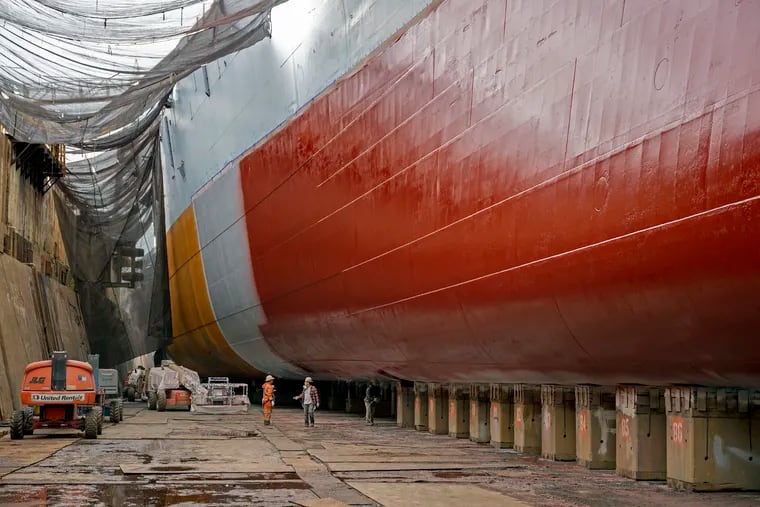 Workers are dwarfed by the hull of the Battleship New Jersey at Philadelphia Ship Repair. The ship is berthed in Dock #3, from which it was launched on  Dec. 7, 1942.