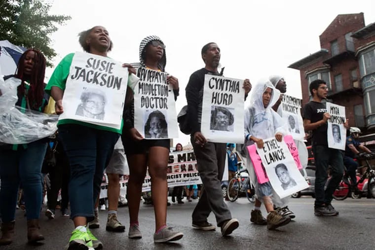 Memorial signs of the nine killed in the Charleston, S.C., church shooting are held during a rally on Broad Street in Philadelphia on Saturday, June 27, 2015. (MICHAEL PRONZATO/Staff Photographer)