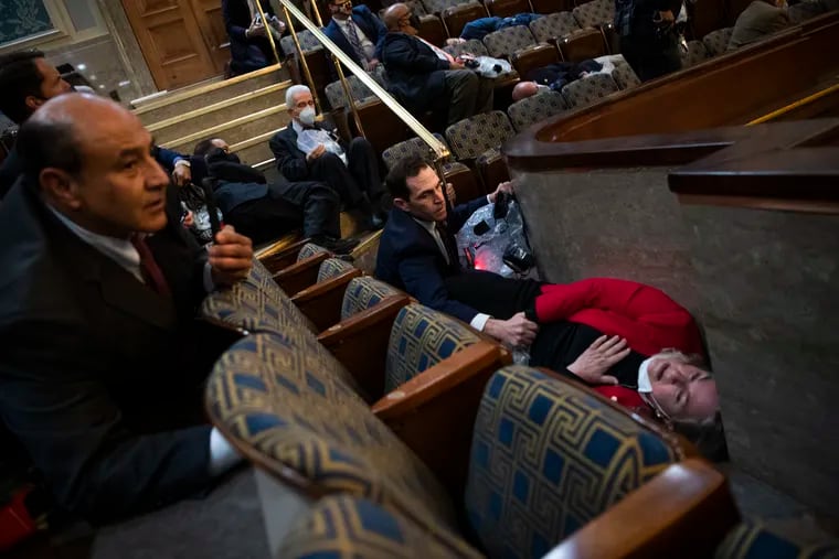 Rep. Jason Crow, (D., Colo.), comforts Rep. Susan Wild, (D, Pa.), while taking cover as rioters disrupt the joint session of Congress to certify the Electoral College vote on Wednesday.