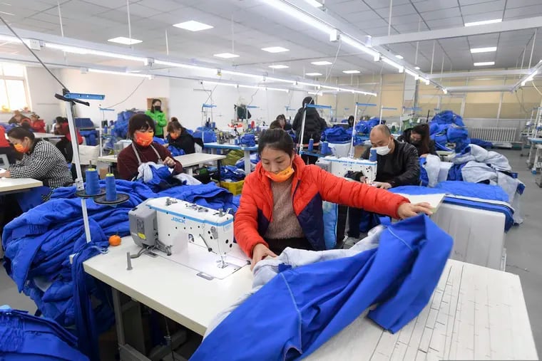 Workers wearing face masks sew fabric in a garment factory in Shenyang in northeastern China's Liaoning Province, Tuesday, Dec. 14, 2021. China reported Wednesday, Dec. 15, 2021, that its economy slowed in November, buffeted by coronavirus outbreaks, weak demand and supply chain disruptions. (Chinatopix via AP)