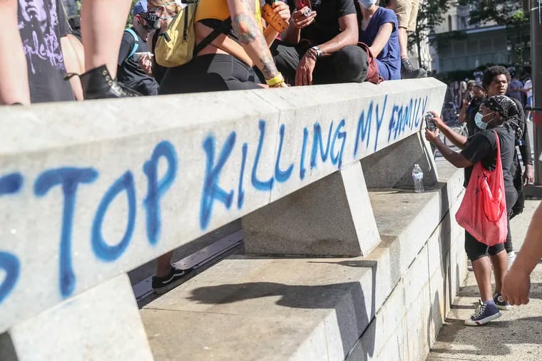 A woman writes "stop killing my family" outside of the MSB building in Philadelphia after a protest against the death of George Floyd.