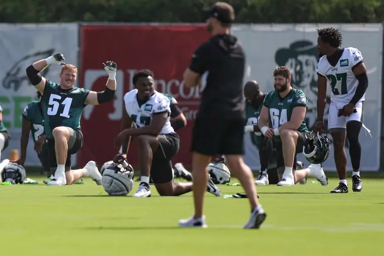 Eagles coach Nick Sirianni looks on while Cam Jurgens, Nakobe Dean and the rest of the team stretches on the first day of training camp at the NovaCare Complex on Wednesday.