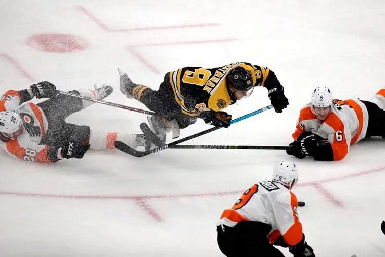 Boston Bruins right wing David Pastrnak (88) goes down as he chases the puck against Philadelphia Flyers center Claude Giroux (28) and defenseman Travis Sanheim (6) in the third period of an NHL hockey game, Thursday, Jan. 31, 2019, in Boston. (AP Photo/Elise Amendola)
