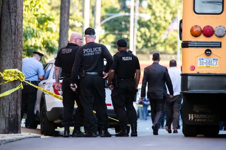 Police walk on the scene of a shooting on Pechin Street behind Roxborough High School in Philadelphia on Tuesday.