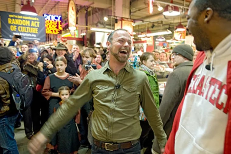 Turning to fellow baritone Norman Garrett, Troy Cook (center) lets out a hearty laugh at the end of the "flash opera" performed at noontime Saturday at Reading Terminal Market. (Clem Murray / Staff Photographer)