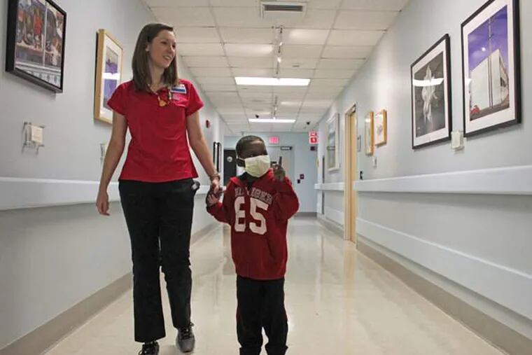 Kaiden Balfour, 6, walks through the Holtz Children's Hospital's seventh floor hall with Elizabeth Carrol, 24, child life specialist, while looking at recently hung artwork. Balfour was diagnosed with leukemia and has recently undergone a bone marrow transplant. (Matias J. Ocner/Miami Herald/TNS)