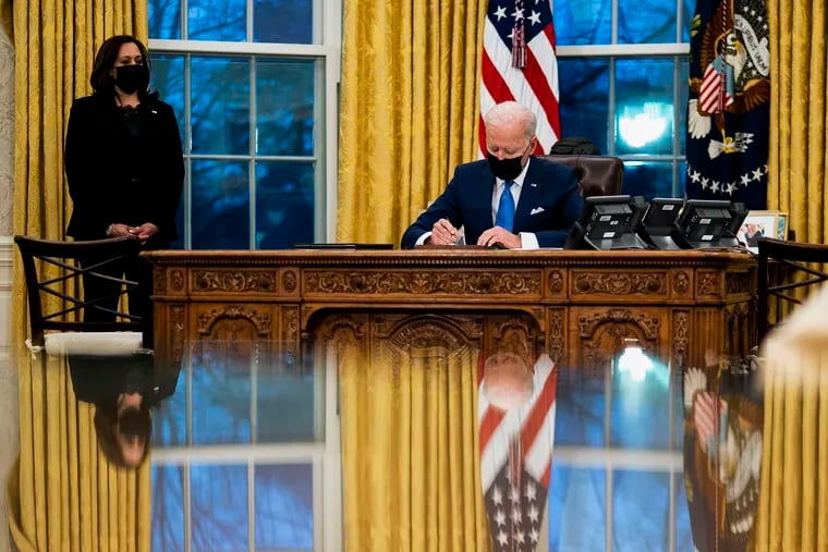 U.S. President Joe Biden signs several executive orders directing immigration actions for his administration as Vice President Kamala Harris looks on in the Oval Office at the White House in Washington, D.C., on Tuesday, Feb. 2, 2021.