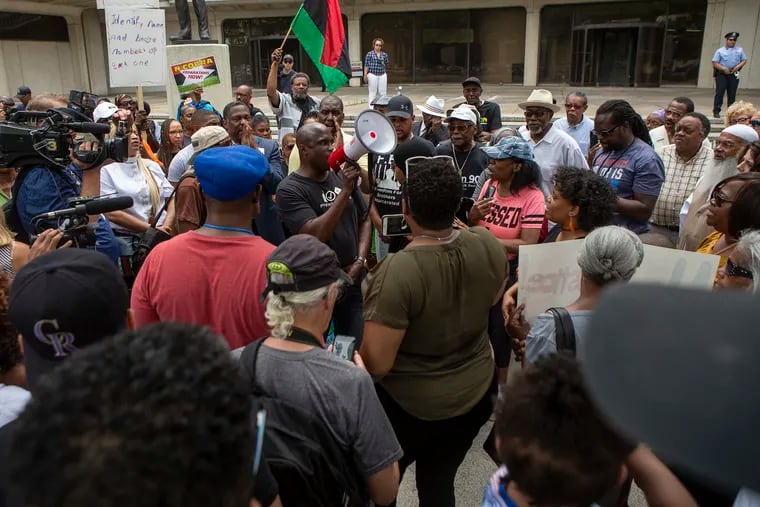 Solomon Jones speaks through a megaphone as a crowd of people gather outside of Philadelphia Police headquarters to protest the 330 active Philadelphia police officers included in a database of racist Facebook comments in June 2019.
