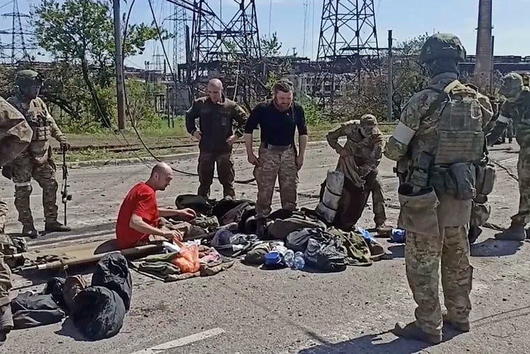 In this photo taken from video released by the Russian Defense Ministry Press Service on Wednesday, Russian servicemen frisk Ukrainian servicemen after they left the besieged Azovstal steel plant in Mariupol.