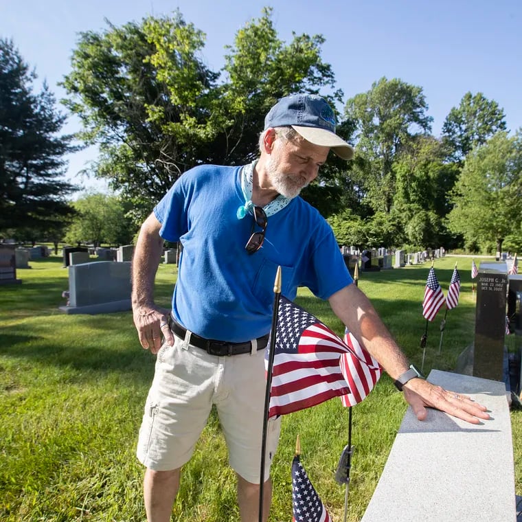 Ken Rucci Sr., 70, of Westbrook Park, started in 2004 placing flags on the grave of his father, Paul Rucci, a World War II Navy veteran, and a few other relatives. It helped him deal with the loss of his father who had passed away in the fall of 2003.  He now places approximately 500 flags on the graves of veterans at SS. Peter and Paul Cemetery in Springfield, Delaware County. Here, he places a hand on his father's grave Friday.