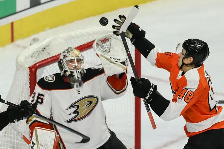 The Flyers' Morgan Frost reaches for a loose puck over Ducks goalie John Gibson during the first period on Tuesday.